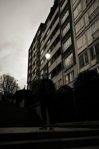 Rear view of man walking on street amidst buildings in city