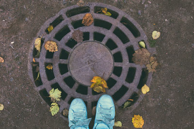 Low section of person standing on manhole