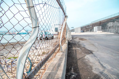 People on beach seen through chainlink fence