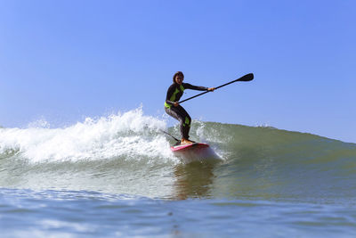 Full length of man surfing in sea against clear sky