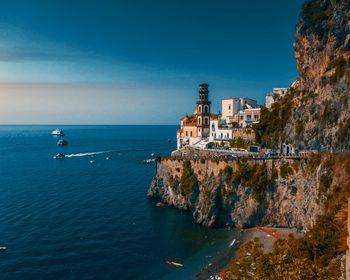 Scenic view of sea by buildings against clear blue sky