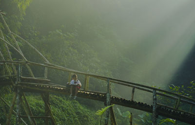 Woman standing on bridge in foggy weather