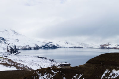 Scenic view of lake by snowcapped mountains against sky