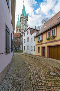 Cobblestone street amidst buildings against sky in city