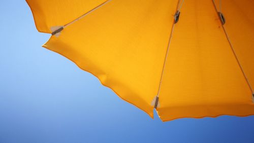 Low angle view of yellow umbrella against clear sky