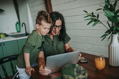 Mother and son using laptop at home