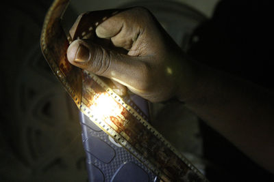 Cropped hand of man holding illuminated light bulb