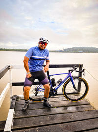 Man riding bicycle on sea against sky