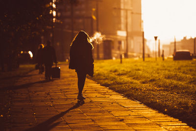 Silhouette woman roller skating on footpath during sunrise