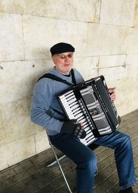 Man wearing hat sitting against wall