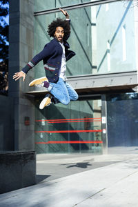 Full length portrait of young man jumping against building