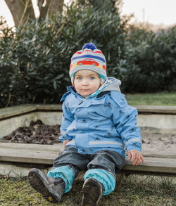 Portrait of cute boy sitting on bench at yard