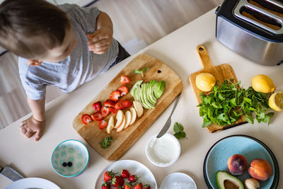 High angle view of boy eating fruit on cutting board