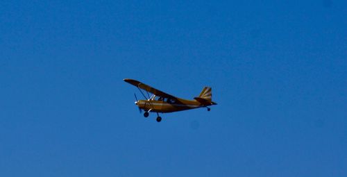 Low angle view of airplane against clear blue sky