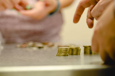 Cropped image of person counting coins on table