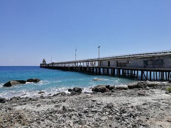 Bridge over sea against clear blue sky