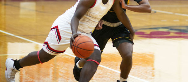 A high school basketball player has one step on his opponent as he id driving to the basket.