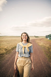 Smiling mature woman with bag walking on road