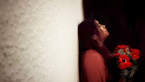 Side view of woman looking at red flowering plants