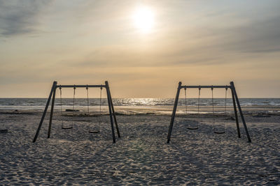 Lifeguard hut on beach against sky during sunset