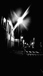 Illuminated street amidst buildings in city at night