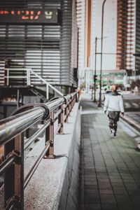 Man walking on footpath amidst buildings in city