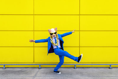 Full length of boy standing against yellow wall