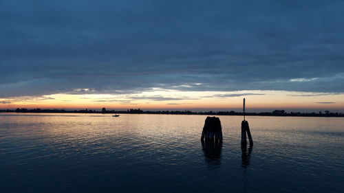 Silhouette people on sea against sky during sunset