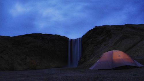 Tent against skogafoss waterfall at dusk