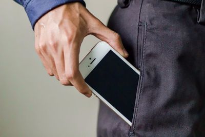 Midsection of man with smart phone in trousers pocket