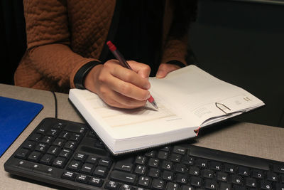 Midsection of man reading book on table