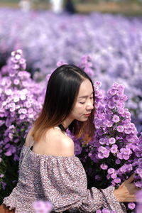 Midsection of woman standing by purple flowering plant