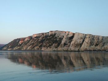 Rock formations by lake against sky