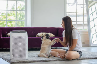 Smiling woman holding dogs paw at home