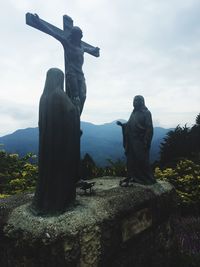 Statue of cross against sky