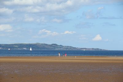 People walking at beach against sky