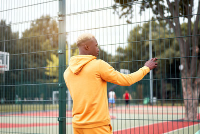Full length of boy playing with fence