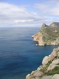 Scenic view of sea by cliff against sky