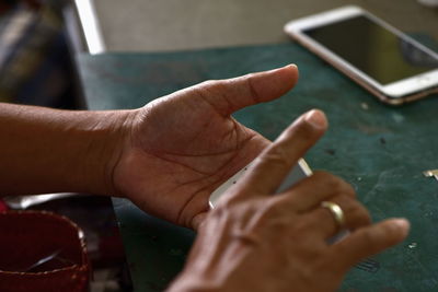 Cropped hands of person using mobile phone on table