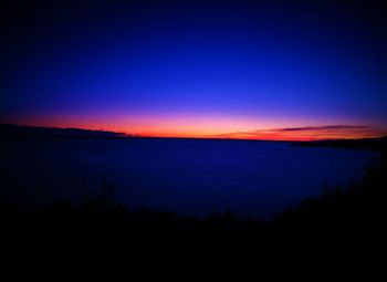 Scenic view of silhouette landscape against blue sky during sunset