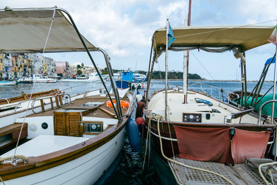 Sailboats moored at harbor against sky