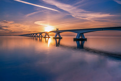 Bridge over sea against sky during sunset