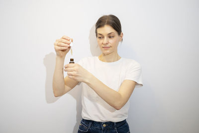 Portrait of smiling young woman gesturing while standing against wall
