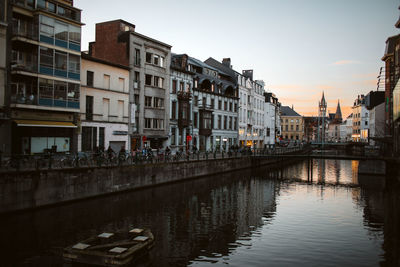 Canal by buildings against sky in city