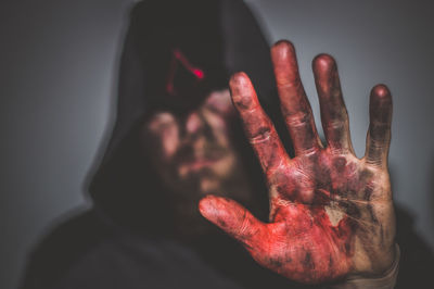 Close-up of man with messy hand gesturing stop sign against gray background