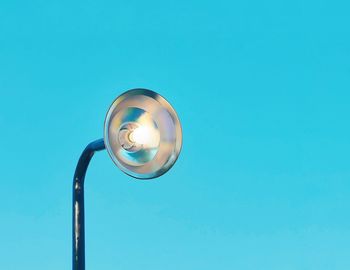 Low angle view of illuminated street light against blue sky