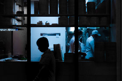 People standing by glass window at night