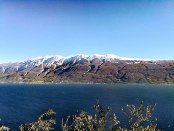 Scenic view of lake and mountains against clear blue sky