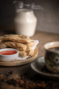 Keropok lekor or fried fish cake on a rattan plate with a sweet chilli sauce and on wooden table. 