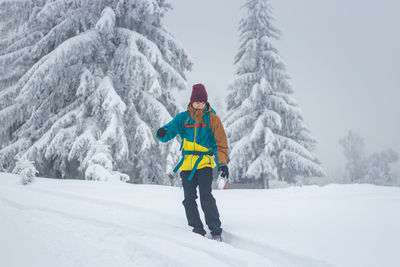 Full length of woman skiing on snow covered field